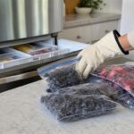Persona retira bolsas genéricas de bayas congeladas de un congelador doméstico